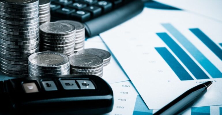 Money, car keys and financials on a desk