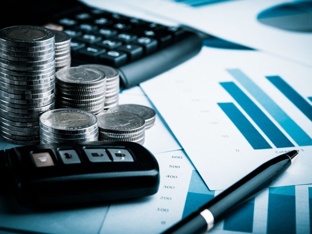 Money, car keys and financials on a desk