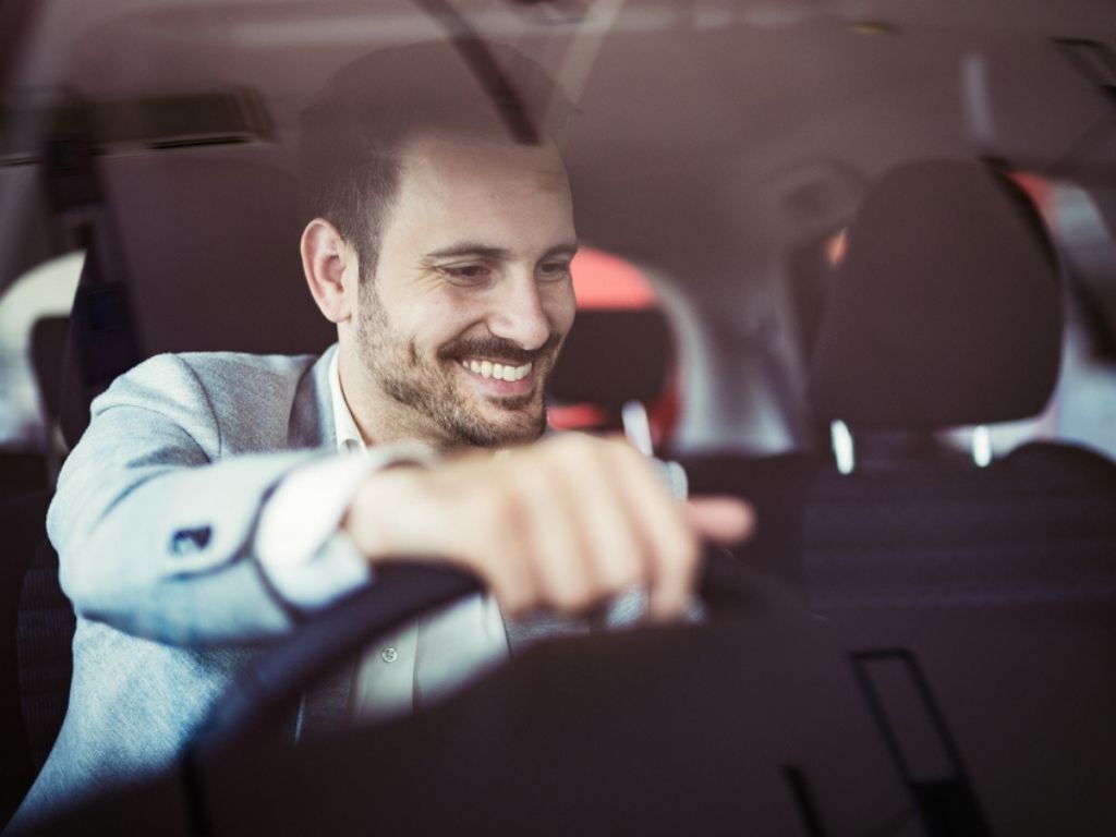 A smiling man behind a car wheel