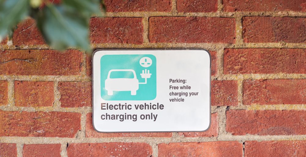 A sign on a brick wall that reads 'electric vehicle charging only'